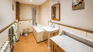 Bagno con toilette, doccia, lavandino e piano di marmo.