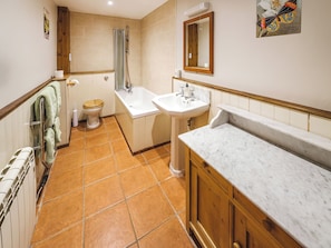 A bathroom with a toilet, shower, sink, and marble countertop.