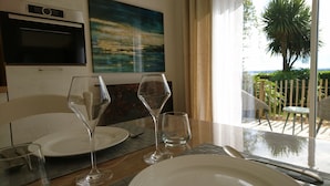 Una mesa de comedor con dos copas de vino, un plato y cubiertos. Hay un cuadro en la pared y un televisor montado sobre la mesa.