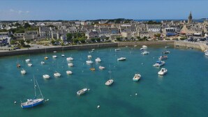 Un puerto con numerosos barcos amarrados, rodeado por un pueblo con edificios históricos y una torre destacada.