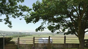 A fenced property with a view of a rural landscape, a tree, and a building with a sloped roof. - Deuglawdd Cottage - HW7788 (Aberdaron, near Pwllheli)
