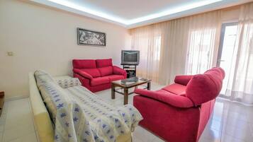 Een woonkamer met een bank, een televisie en een bed.