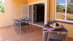 A small dining area with a table and chairs, a sliding glass door, and a window with a view of the outside.