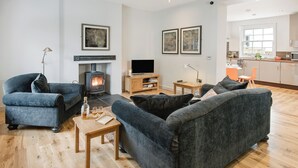 Una sala de estar moderna con chimenea, sofás, televisor y una zona de cocina.