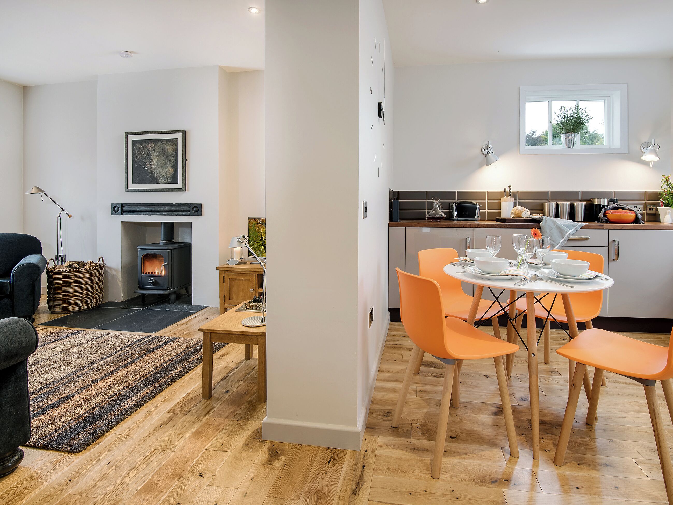 A modern kitchen with a dining area, a fireplace, and a view of the outdoors.