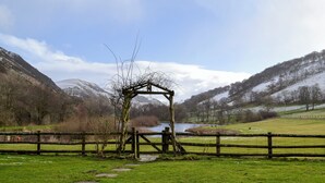 A rustic wooden structure in a grassy field with a mountain backdrop. - 1 bedroom accommodation in Newbridge-on-Wye, near Builth Wells (Newbridge-on-Wye, near Builth Wells)