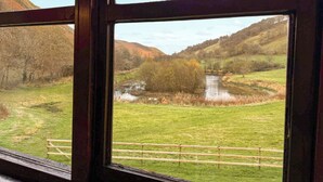 A window view of a rural landscape with a river, grassy fields, and hills. - 1 bedroom accommodation in Newbridge-on-Wye, near Builth Wells (Newbridge-on-Wye, near Builth Wells)