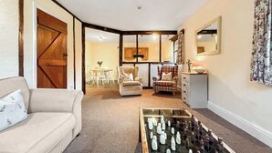 A cozy living room with a sofa, a coffee table with a chess set, a dining area with chairs and a table, and a kitchen area with cabinets and a mirror. - 1 bedroom accommodation in Newbridge-on-Wye, near Builth Wells (Newbridge-on-Wye, near Builth Wells)