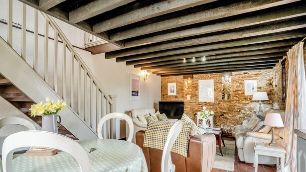A cozy living room with a fireplace, stone wall, and a staircase. - 2 bedroom accommodation in Gowerton, Gower (Gowerton, Gower)