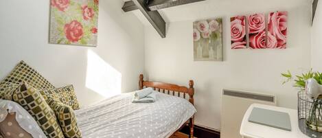 Un dormitorio con cama, radiador, tragaluz y decoración floral en la pared.