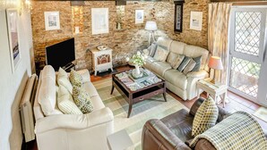 A cozy living room with stone walls, a fireplace, a sofa set, and a coffee table. - 2 bedroom accommodation in Gowerton, Gower (Gowerton, Gower)