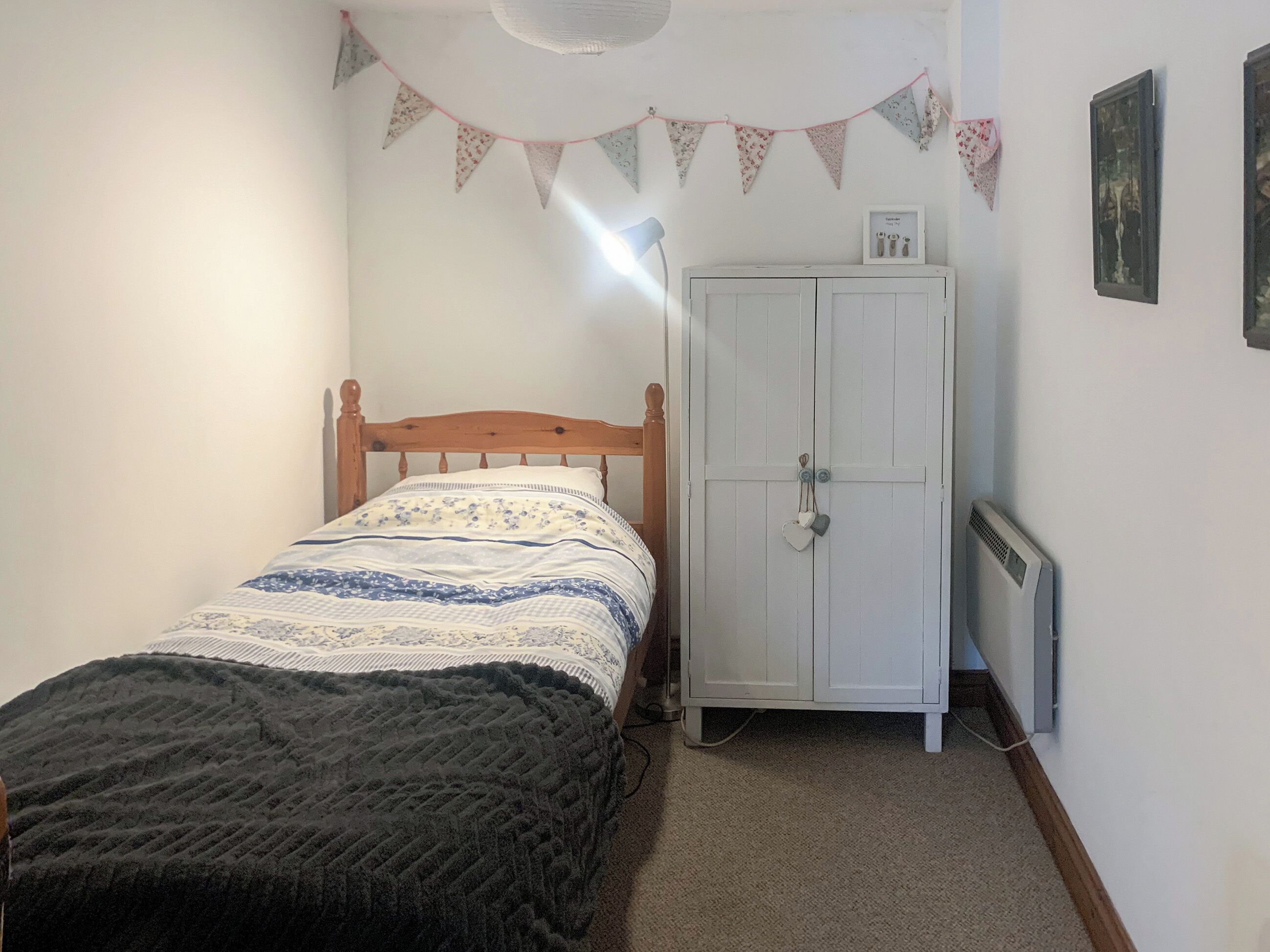 A bedroom with a wooden bed, a white wardrobe, and a radiator.