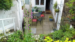 A small patio with a table and chairs, surrounded by potted plants and flowers.