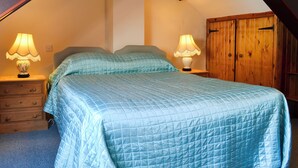 A bedroom with a bed, two bedside tables with lamps, a wooden wardrobe, and a sloped ceiling. - 1 bedroom accommodation in Once Brewed, Bardon Mill, near Hexham (Once Brewed, Bardon Mill, near Hexham)