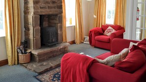 A cozy living room with a stone fireplace, red sofas, and yellow curtains. - 1 bedroom accommodation in Once Brewed, Bardon Mill, near Hexham (Once Brewed, Bardon Mill, near Hexham)