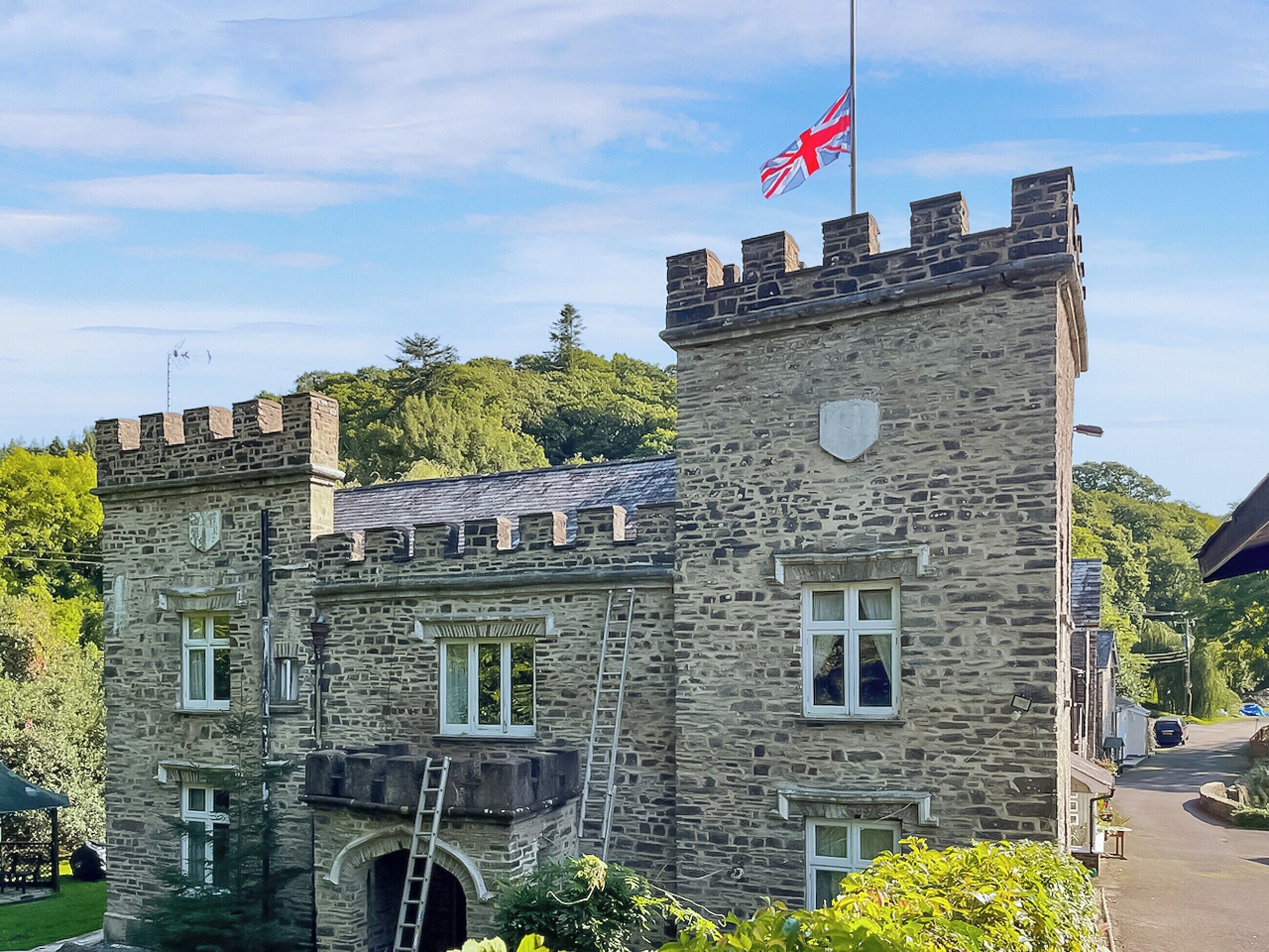A stone building with a flag, windows, and a tower.