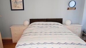 Una camera da letto con un letto, due comodini, una lampada a parete, un quadro incorniciato e uno specchio.