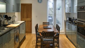 Una cucina moderna con pavimento in legno, un tavolo da pranzo con sedie e un'ampia finestra con persiane.