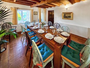 A dining room with a wooden table set for a meal, surrounded by chairs with cushioned seats.