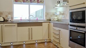 Eine moderne Küche mit Fenster, Edelstahlgeräten und einer Fliesenküchenrückwand.