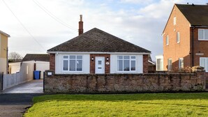 A two-story house with a stone wall in front, a tiled roof, and a brick exterior. - 3 bedroom accommodation in Beadnell (Beadnell)
