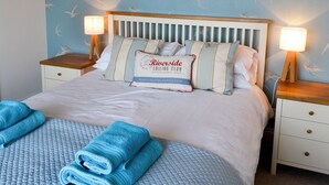 A neatly made bed with a pillow featuring the text "Riverside Sailing Club Established 1983". - 3 bedroom accommodation in Beadnell (Beadnell)