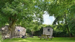 Et rustikt udendørs miljø med et træskur, et picnicbord og en stenvæg.