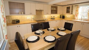 Een moderne keuken met witte kastjes, een houten aanrecht en een eettafel voor zes personen met zwarte stoelen.