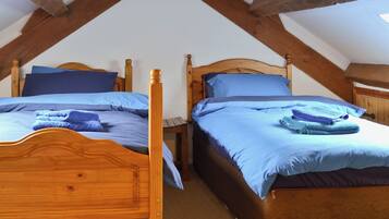 Two wooden beds with blue bedding in a room with exposed wooden beams.
