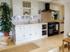 A kitchen with white cabinetry, a black stove, and a potted plant.