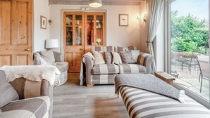 A cozy living room with a large window, wooden beams on the ceiling, and a dining area with a view. - 4 bedroom accommodation in Rosedale Abbey (Rosedale Abbey)