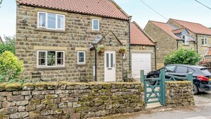 A stone house with a tiled roof, a stone wall, and a car parked outside. - 4 bedroom accommodation in Rosedale Abbey (Rosedale Abbey)
