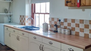 Eine Küche mit Spüle, Schränken, einem Fenster und einer Kaffeemaschine.