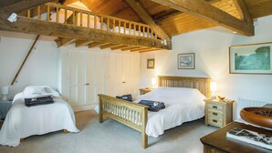 A bedroom with two beds, wooden beams, white walls, and a loft bed. - Castle House Cottage (Hartley, near Kirkby Stephen)