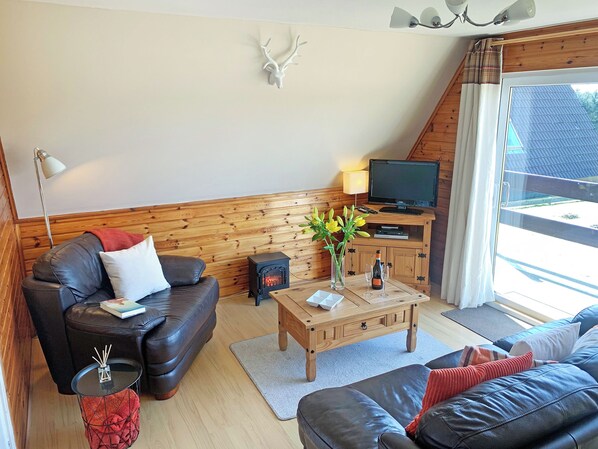 A cozy living room with a leather sofa, a wooden coffee table, a television, and a fireplace.
