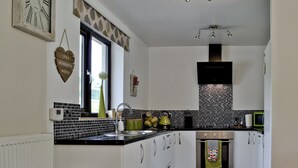 A modern kitchen with white cabinets, black countertops, and a black and white tiled backsplash.