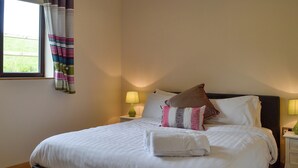 A neatly made bed with white linens, a brown headboard, and two bedside lamps.