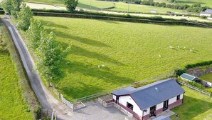 A rural property with a large fenced pasture, a stable, and a building with a red roof.