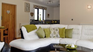 A modern living room with a white sectional sofa, a glass coffee table, and a wooden dining table with chairs.