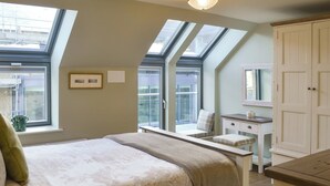 Un dormitorio con cama, cómoda, espejo y tragaluces.