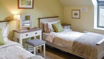 A bedroom with two beds, a desk, a chair, and a window.