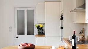 Eine moderne Küche mit einer Holzauskładung, einer Schüssel Äpfel, einer Weinflasche und einer Vase mit Blumen.