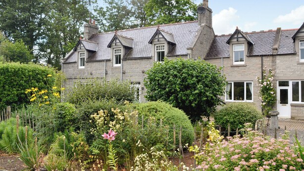 Ein Steinhaus mit Garten, mit verschiedenen Pflanzen und Blumen.