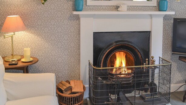 A living room with a fireplace, a mirror, and two blue vases on the mantel.