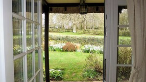 A doorway leading to a garden with a lawn, hedges, and a tree. - 2 bedroom accommodation in Otterton (Otterton)