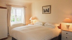 A bedroom with a bed, two bedside tables with lamps, a window with curtains, and a framed picture on the wall. - 2 bedroom accommodation in Otterton (Otterton)
