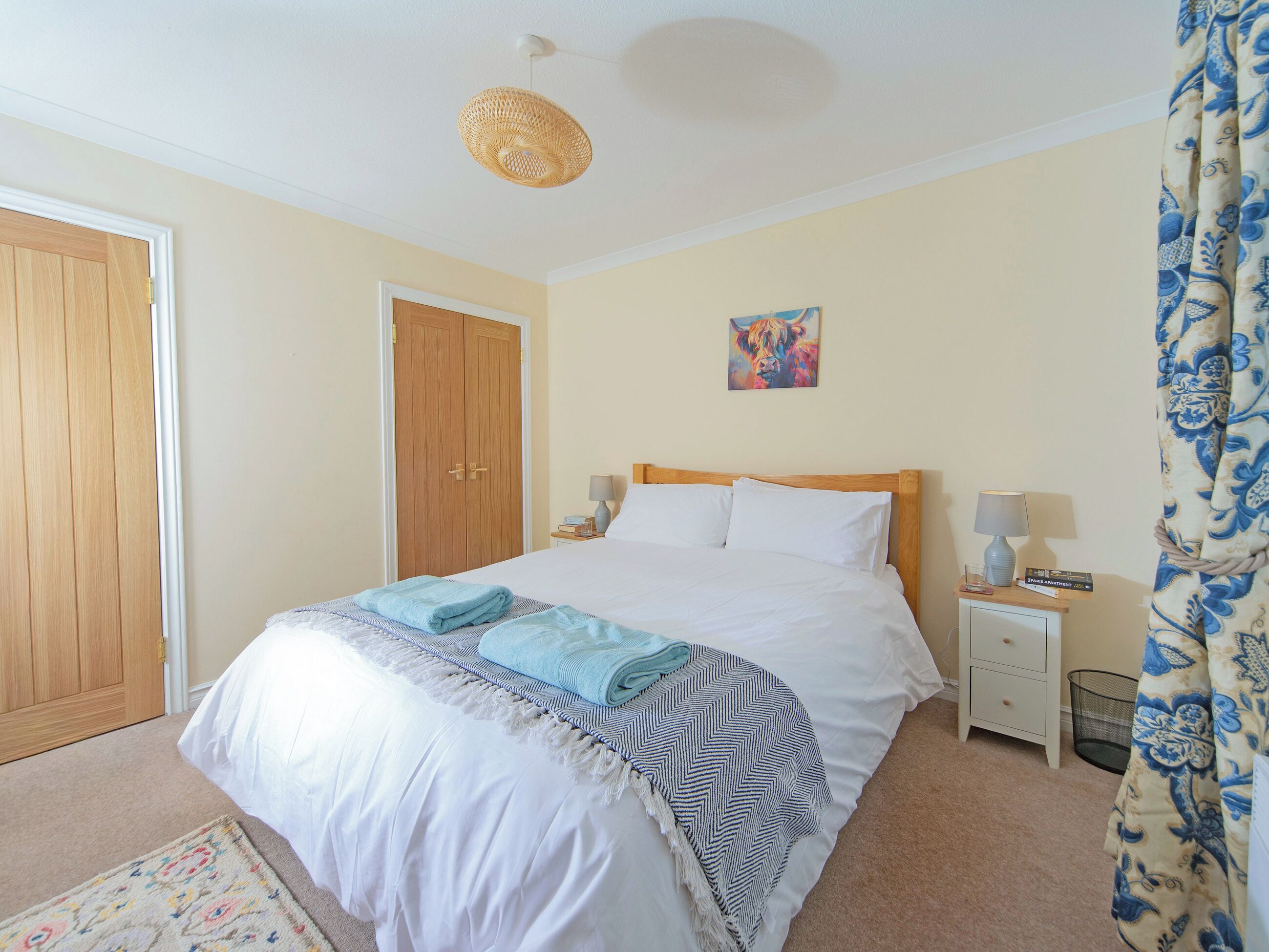 A bedroom with a bed, bedside tables, a lamp, a painting, and a door.