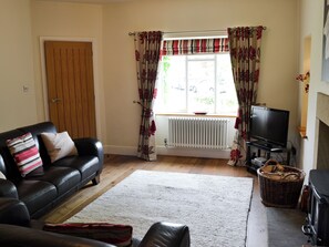 A living room with a sofa, a television, a fireplace, and a window with curtains.