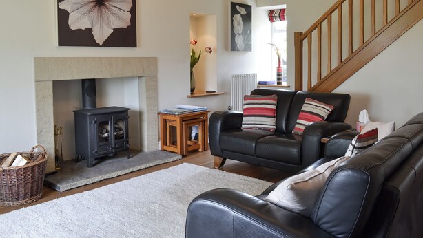 A living room with a fireplace, a sofa, a staircase, and a large flower painting. - 3 bedroom accommodation in Burnsall (Burnsall)