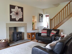 A living room with a fireplace, a sofa, a staircase, and a large flower painting.